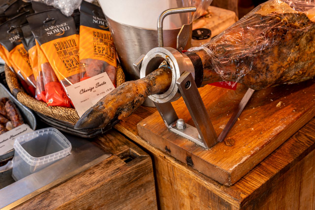 why-choose-us Close-up of cured meats including Spanish ham and chorizo in a gourmet shop display.