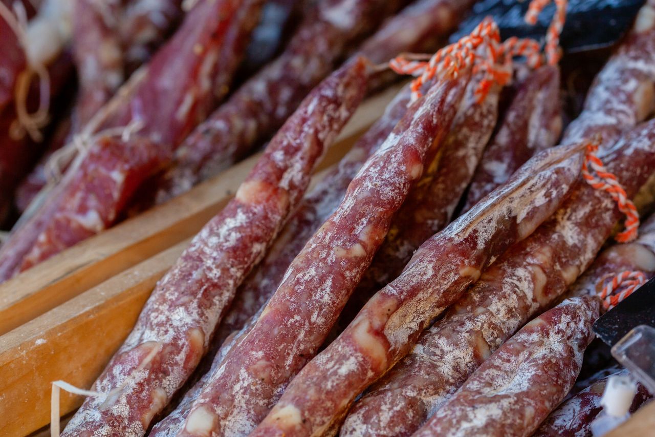 contact-img A detailed close-up of traditional Italian salami sticks arranged in rows, showcasing their texture.
